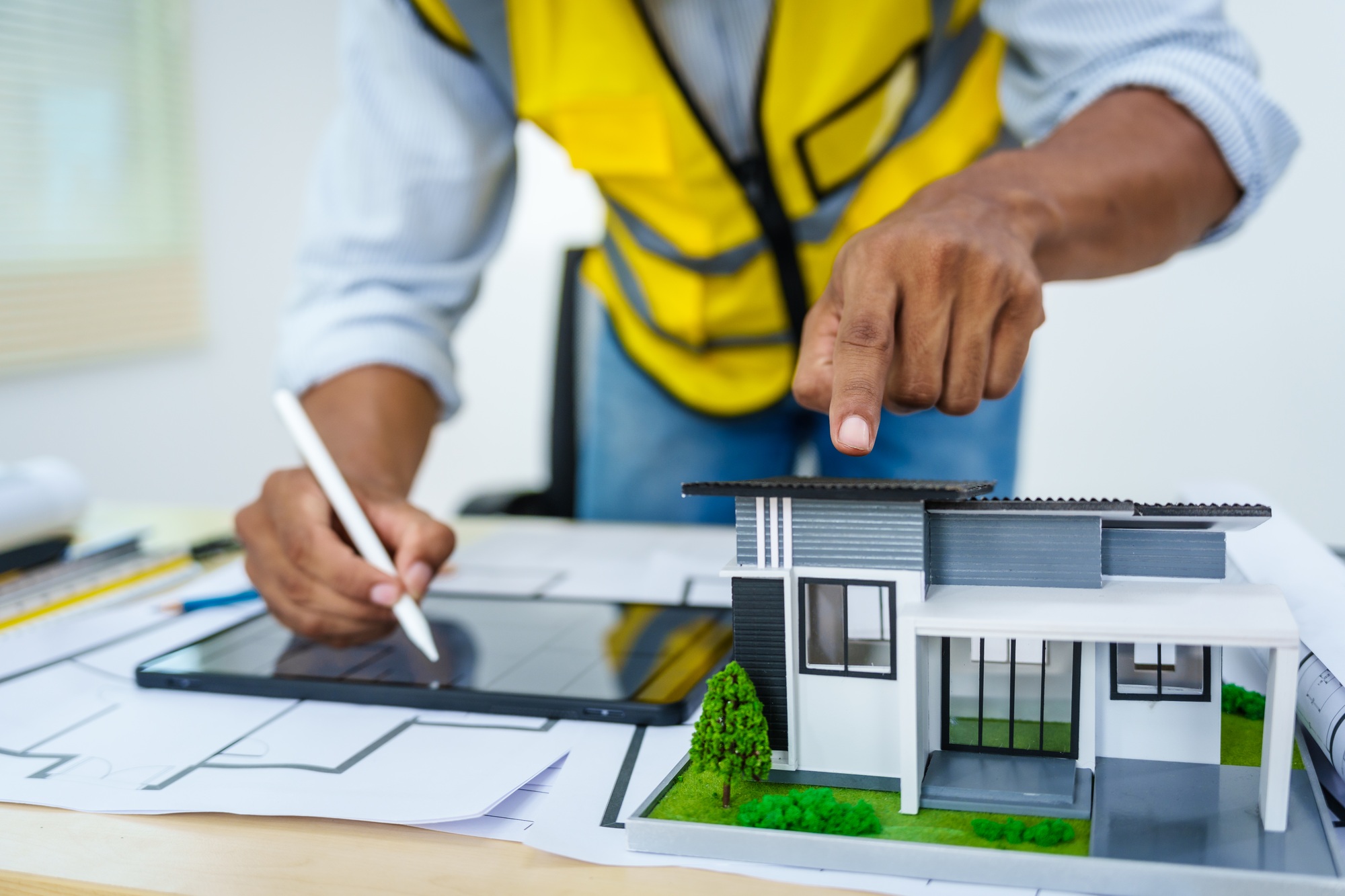 Asian architect: house model, blueprints, real estate law, zoning, permits, disputes.