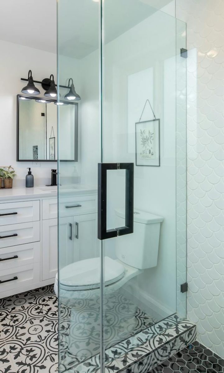 Photo by Terry Magallanes Elegant white bathroom with glass shower and stylish patterned floor.