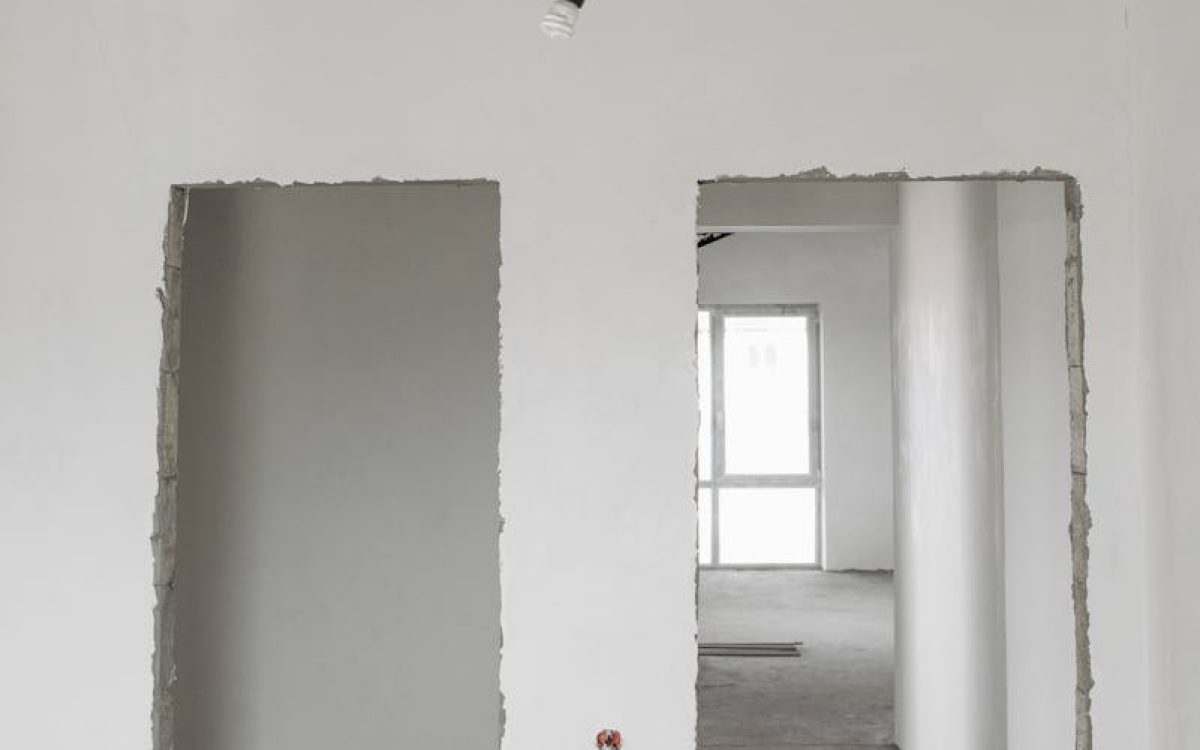 Unfinished room interior with white plastered walls and exposed ceiling in a construction site.