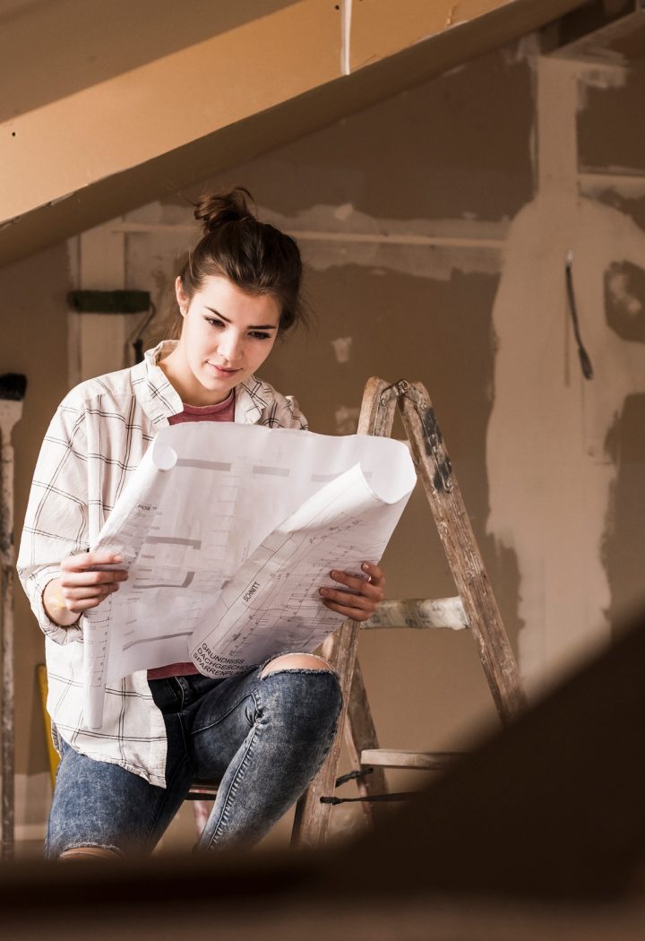 Young woman renovating her new home, holding construction plan
