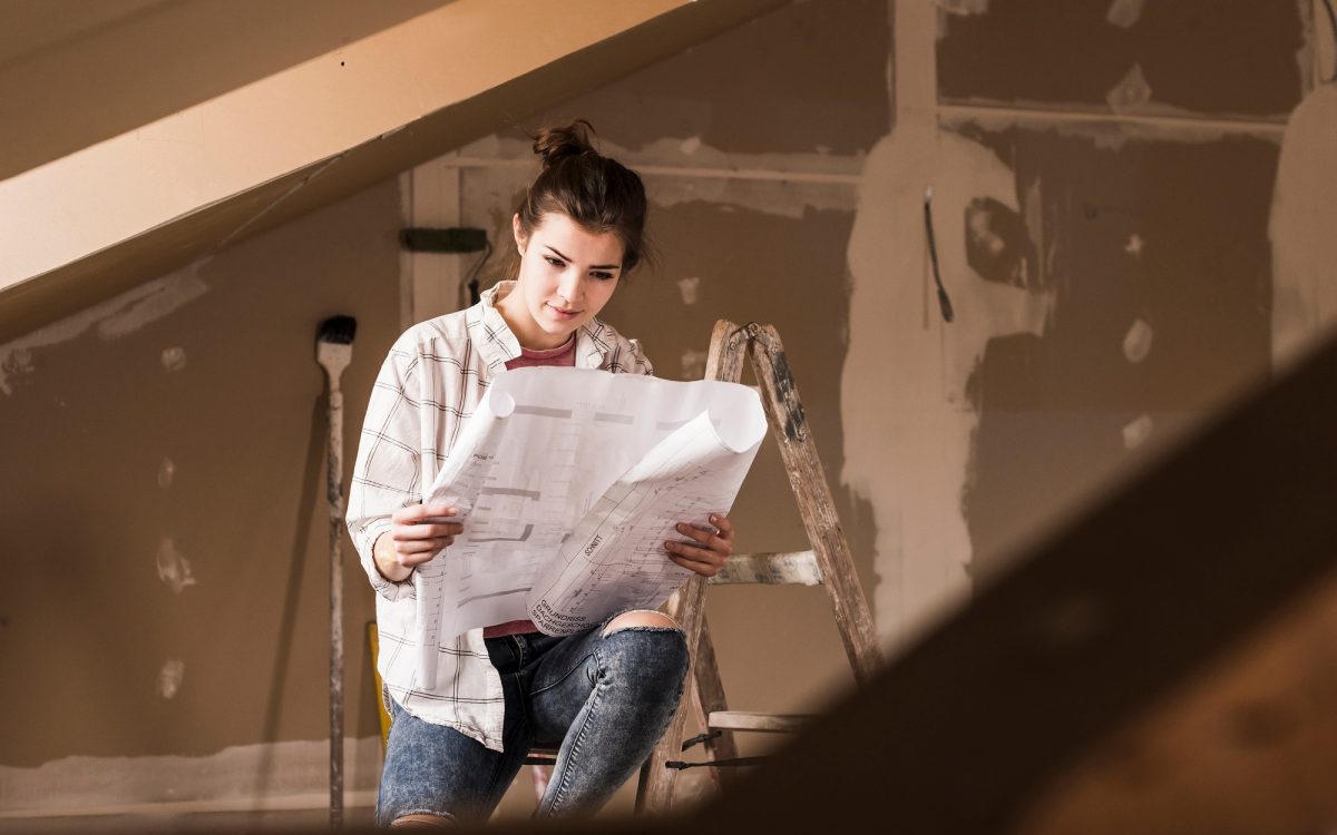 Young woman renovating her new home, holding construction plan Young woman renovating her new home, holding construction plan